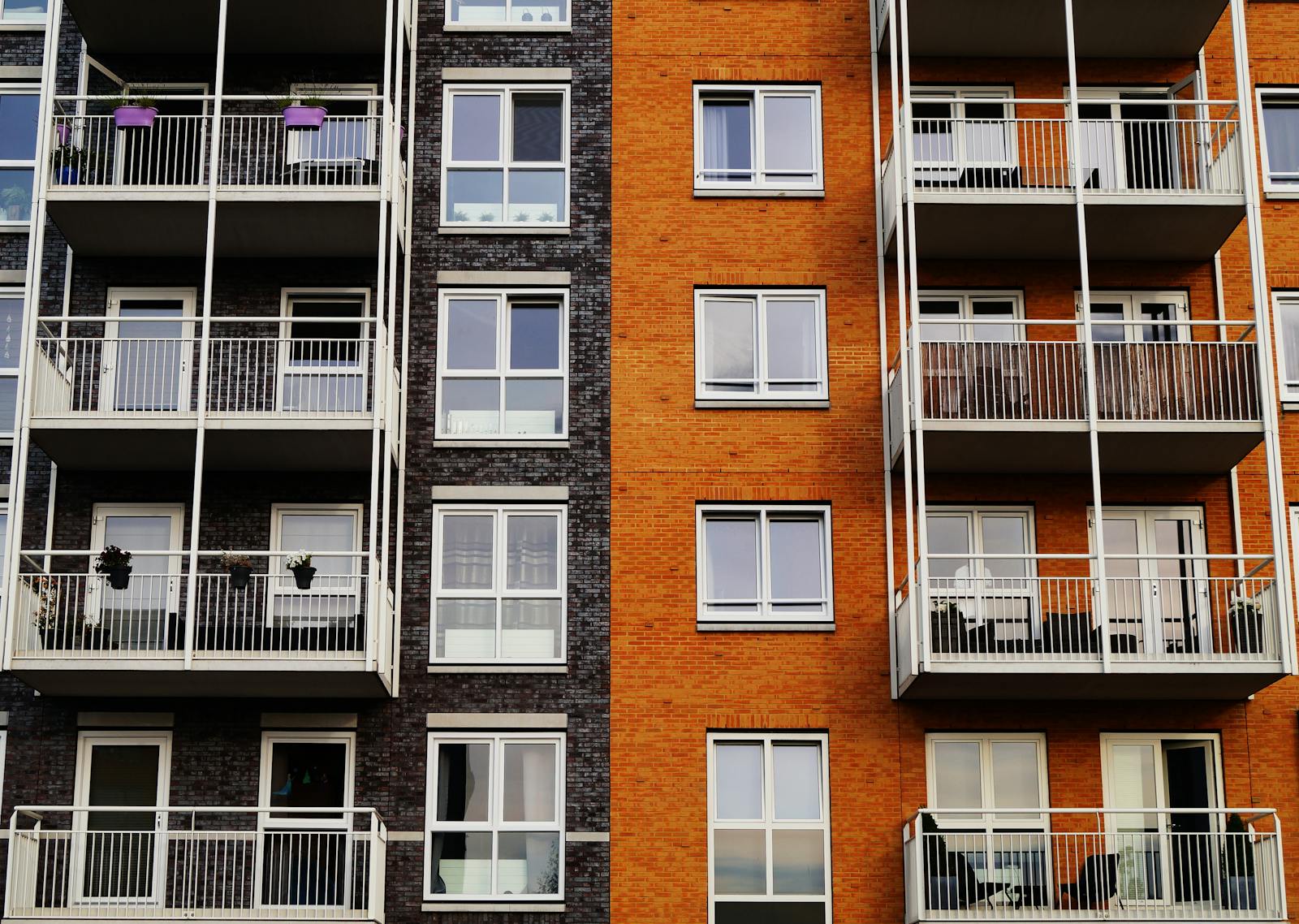 renters insurance, Detailed view of a modern apartment building's exterior with balconies and glass windows.